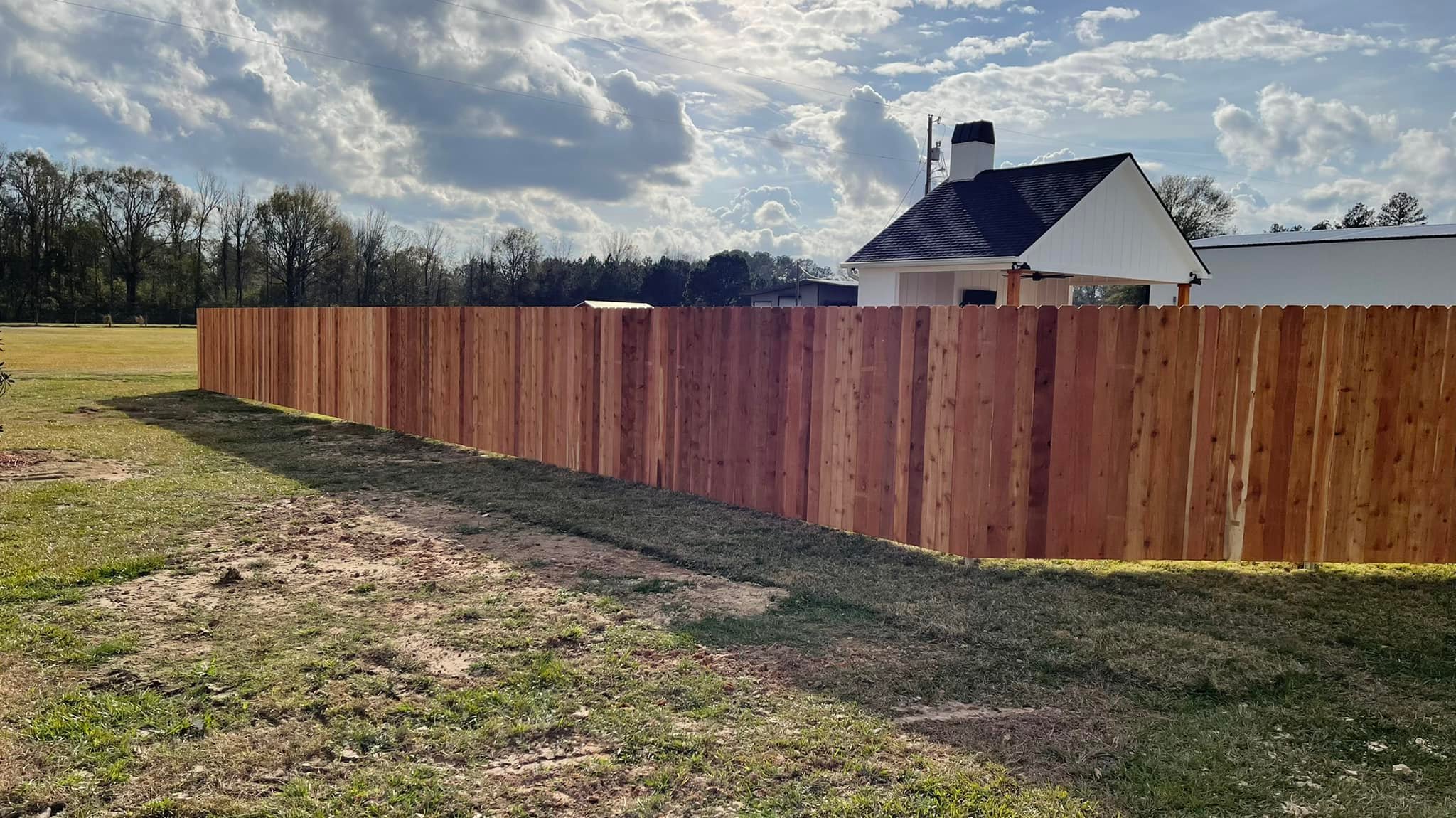 Long run of cedar fence with house in background