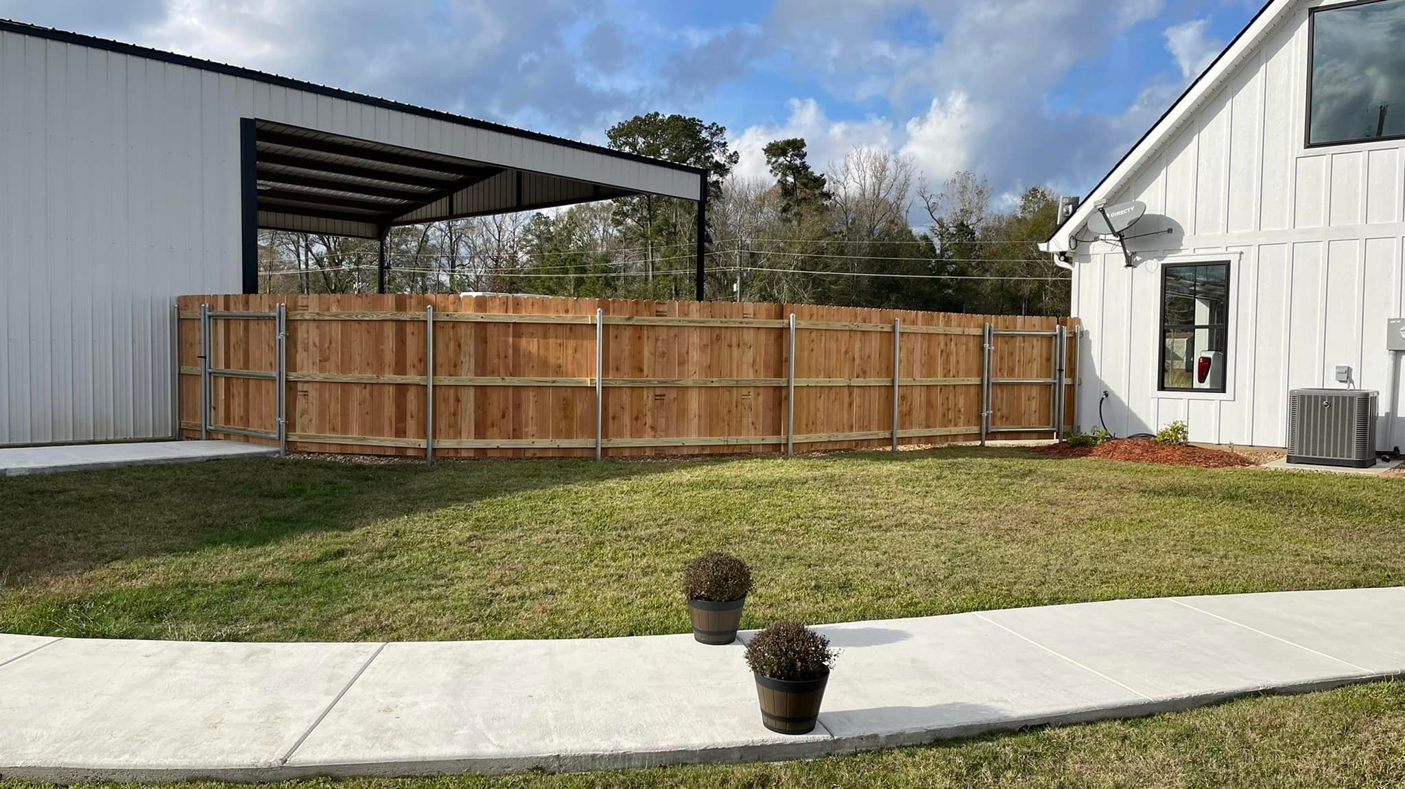 Cedar fence with steel gate posts and metal building