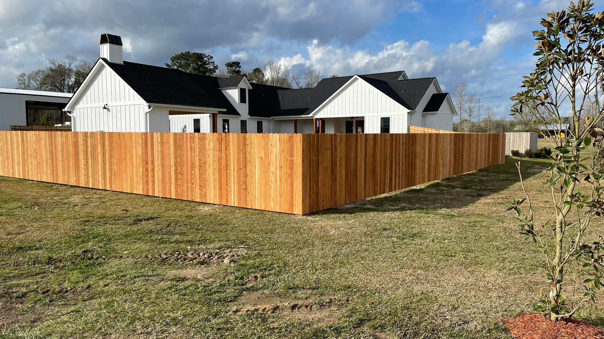 Full cedar privacy fence around a white farmhouse